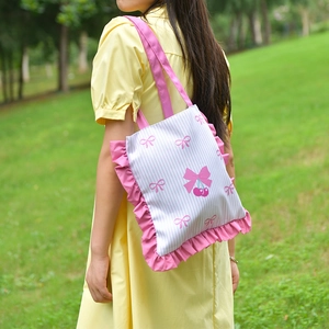 Close-up of pink striped canvas tote bag with ruffled edges and cherry bow pattern
