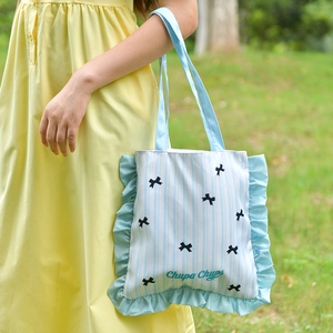 Detail of blue striped canvas tote with black bows and frilly ruffled edges