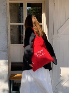 Rote Segeltuchtasche mit Island Naomi Buchstabendruck in sonnigem Außenbereich