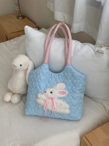 Close-up of plush rabbit embroidery and heart quilted fabric on a light blue canvas bag