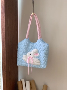 Detail of light blue quilted tote bag with heart patterns and plush rabbit embroidery