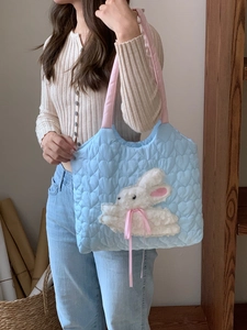 Detail of light blue quilted tote bag with white plush bunny embroidery and pink straps