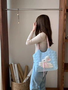 Detail of blue heart quilted canvas tote bag featuring 3D plush bunny and pink strap