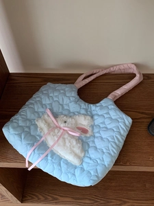 Close-up of quilted heart patterns and plush rabbit on a blue canvas shoulder bag