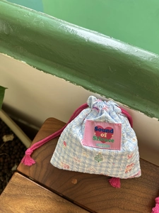 Dettaglio della borsa a coulisse a quadretti blu con stampe e toppa rosa