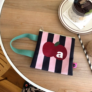Detail van roze gestreepte canvas tas met appelprint en groen handvat