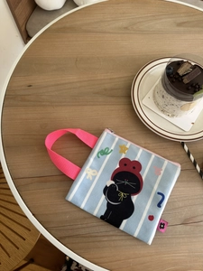 Blauwe gestreepte canvas minitas met schattige zwarte kat op houten tafel
