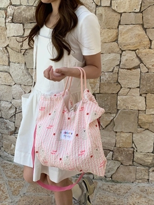 Close-up of pink quilted canvas bag with cute cherry and bear patterns for casual use