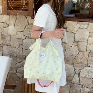 Detail of light yellow textured canvas tote bag featuring cute animal prints and pink straps