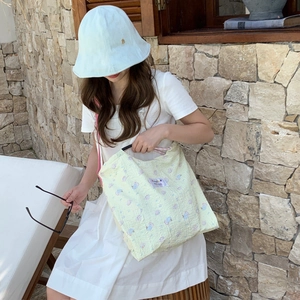 Detail of yellow floral canvas shoulder bag and light blue hat in a summer setting