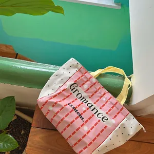 Detail view of pink plaid and polka dot canvas tote bag with yellow handle and zipper
