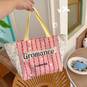 Detail of yellow fabric handles and zipper closure on a large checkered canvas tote bag