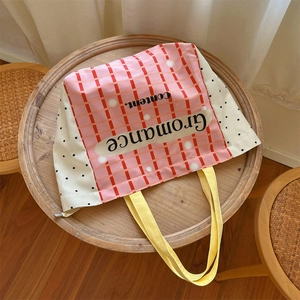 Close-up of pink checkered canvas tote with black lettering on a rustic wooden table