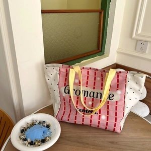 Detail of yellow canvas tote bag handle with pink plaid pattern and Gromance text