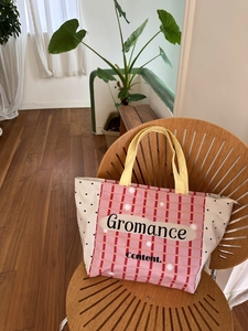 Detail of canvas tote bag with pink plaid, dots, yellow handles on a wooden chair