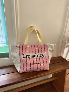 Detail of pink and yellow checkered canvas tote bag with black dots and letter print