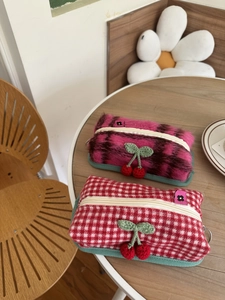 Détails de cerises tricotées sur des pochettes de rangement en peluche et vichy