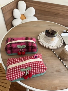 Gros plan de pochettes à carreaux tricotées avec décor de cerises au crochet sur bois