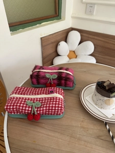 Vue détaillée des cerises tricotées main sur un ensemble de pochettes à carreaux