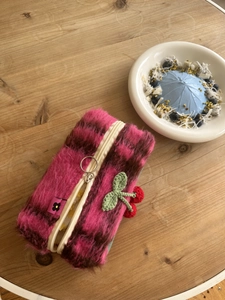 Gros plan d'une pochette en peluche à carreaux rose avec un charme cerise tricoté