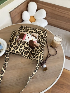 Detail of leopard print canvas bag with plush puppy patch and decorative charms