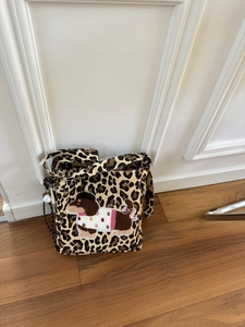 Detail of leopard print canvas bag featuring a 3D cartoon dachshund patch and baseball charm