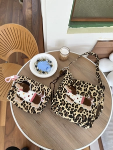 Detail of leopard print canvas bag with cartoon dog embroidery and matching pouch on table