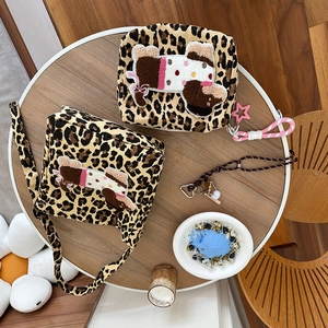 Close-up of leopard print canvas bag set with embroidered poodle on a wooden table