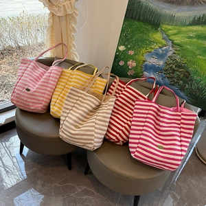 Macro view of textured striped canvas tote bags with handmade leather patch detail