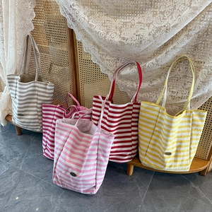 Close-up of colorful striped canvas tote bags with leather labels in various vibrant tones