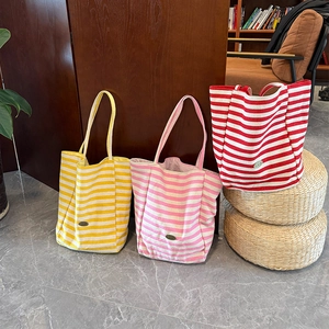 Detailed view of large striped canvas tote bags in yellow, pink and red colors