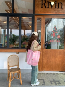 Lifestyle shot of large pink and white striped canvas tote bag worn over the shoulder