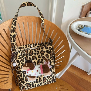 Vintage leopard canvas tote bag with dog embroidery and mini baseball charm hanging on chair