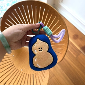 Close-up of cute plush doll keychain with embroidery details and braided rope