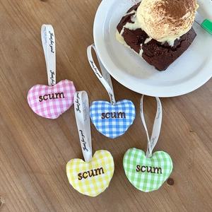 Porte-clés cœur en peluche à carreaux rose, bleu, jaune et vert sur table en bois