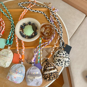 Detail view of mini backpack pouches with colorful braided straps on a wooden tray