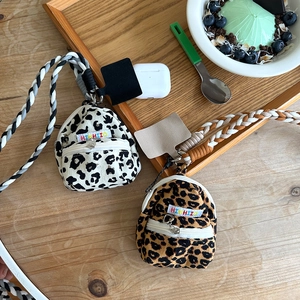 Close-up of mini leopard print earphone bags with woven lanyards on a wooden table
