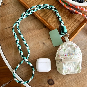 Detailed view of floral mini backpack pouch with a green woven lanyard on a wooden desk