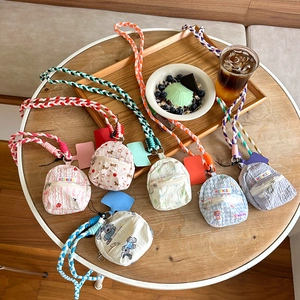 Mini backpack-shaped coin purses with cute patterns and woven straps on a wooden table