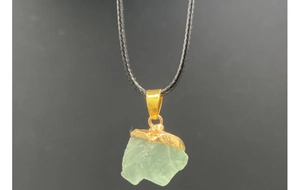 Primer plano del colgante de piedra natural verde translúcida con cordón negro trenzado