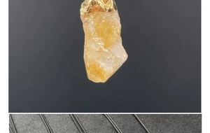 Primer plano de colgante de piedra sol natural con enganche dorado sobre soporte negro
