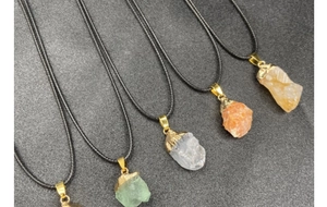 Vista detallada de cinco collares de cristal en bruto con baño de oro y cordones negros