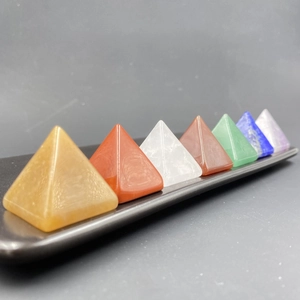 Lot de sept pyramides en pierres naturelles colorées pour chakra sur un plateau sombre