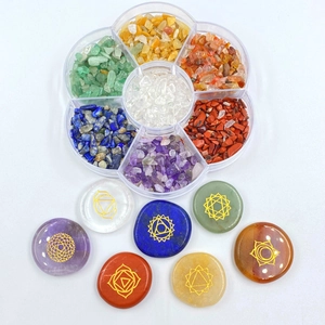 Detalle de siete piedras chakra con símbolos dorados y caja de cristales en pétalo