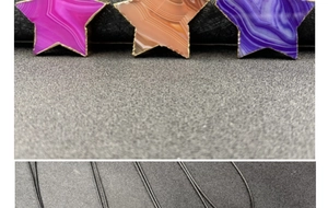 Detalle de colgantes de ágata en forma de estrella con bordes dorados y cordón negro