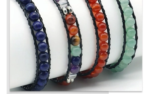 Détail de bracelets multi-rangs en cuir et pierres naturelles sur présentoir blanc