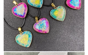 Detail of colorful imperial stone heart pendant with gold-plated edges and black cord