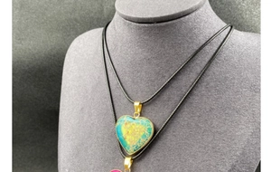 Detail of heart-shaped emperor stone pendant with gold-plated edge on a black cord