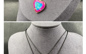 Detail of a colorful heart-shaped stone pendant with gold plating and a black cord necklace