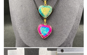 Detail of colorful heart-shaped stone pendants with gold plating on grey display